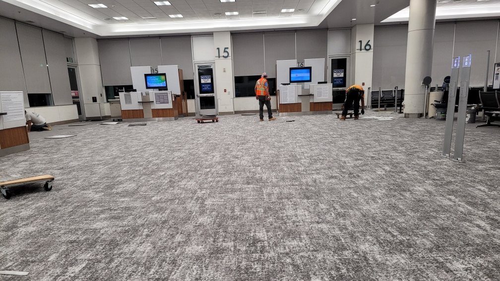 CALTEC crew replacing gate-area carpet overnight at Palm Springs International Airport, with the terminal intact around the work.